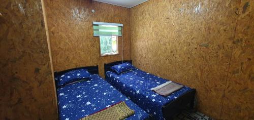 a small bedroom with two beds and a window at Chalet Kampong Guar, Manong in Kuala Kangsar