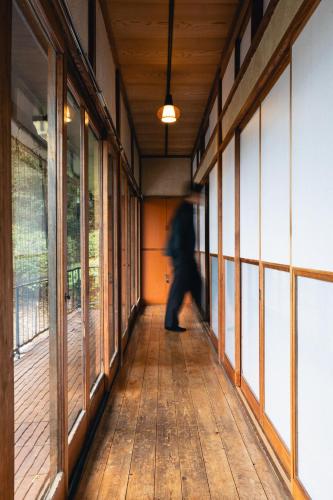 a person walking down a hallway in a building at mysa hakone in Hakone