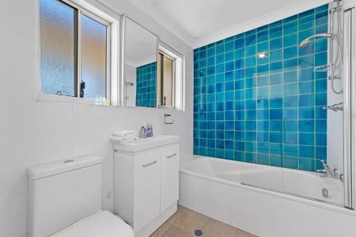 a bathroom with a white tub and a blue tiled wall at Ocean View 1 bedroom Private Apartment next to Maroubra Beach in Sydney