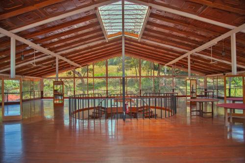 Habitación grande con suelo de madera, ventanas y mesas. en Hotel Martino Spa and Resort, en Alajuela