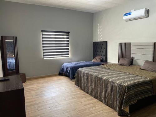 a bedroom with two beds and a air conditioner at Casa Granada cercana a consulado y aeropuerto. in Ciudad Juárez