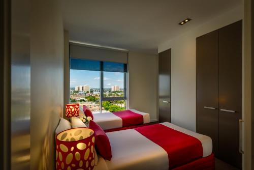 a bedroom with two beds and a large window at Adele Apartment Hotel East Melbourne in Melbourne
