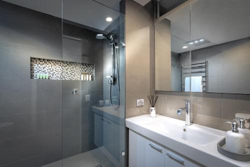 a bathroom with a sink and a shower with a mirror at Adele Apartment Hotel East Melbourne in Melbourne