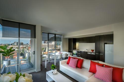 a living room with a white couch and red pillows at Adele Apartment Hotel East Melbourne in Melbourne