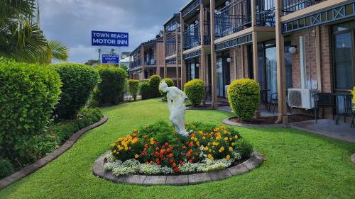 uma estátua num jardim em frente a um edifício em Town Beach Motor Inn Port Macquarie em Port Macquarie