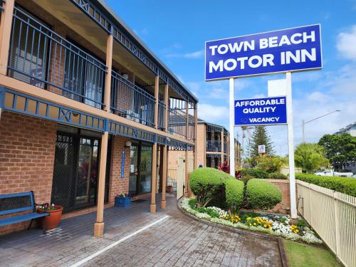 Town Beach Motor Inn Port Macquarie في ميناء ماكواري: لافتة نزل على شاطئ المدينة أمام مبنى