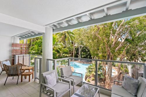 a balcony with chairs and a swimming pool at Belle Escapes Drift Beachfront Resort Suite 1305 in Palm Cove