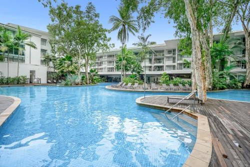 an outdoor swimming pool with a resort building in the background at Belle Escapes Drift Beachfront Resort Suite 1305 in Palm Cove