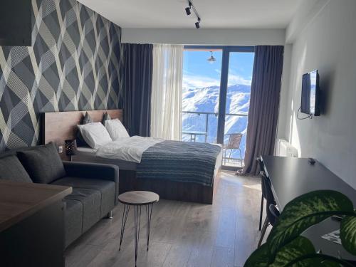 - une chambre avec un lit, un canapé et une fenêtre dans l'établissement gudauri amazing mountain view, à Goudaouri