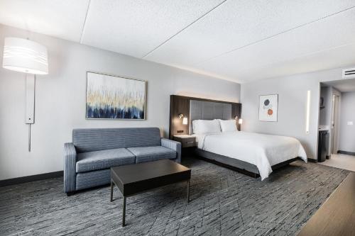 a hotel room with a bed and a couch at Holiday Inn Express & Suites Toronto Airport South by IHG in Toronto