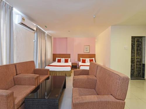 a hotel room with two beds and a couch at MRC Hotel Melaka Raya in Melaka