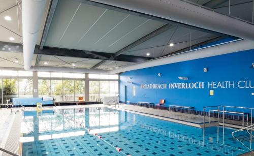 a large swimming pool with a blue wall at The Retreat Inverloch in Inverloch
