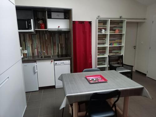 eine Küche mit einem Tisch und einem roten Vorhang in der Unterkunft l'annexe du jardin in Saint-Doulchard