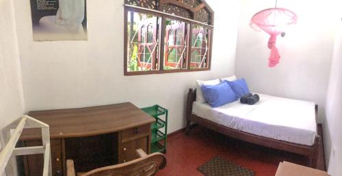 a room with a bed and a table and a window at Delight Homestay in Ahangama