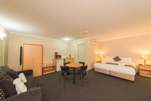 a hotel room with a bed and a table at Harbour Sails Motor Inn in Gladstone