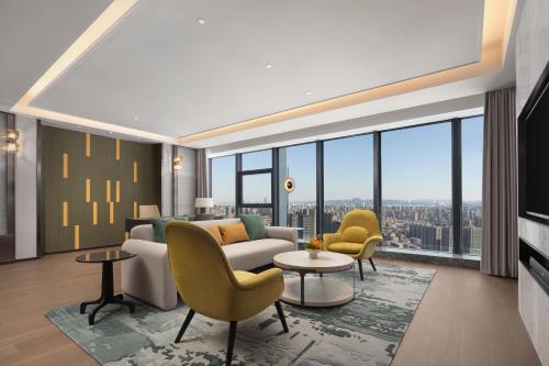 a living room with a couch and chairs and large windows at Crowne Plaza Jinan Runhua in Jinan