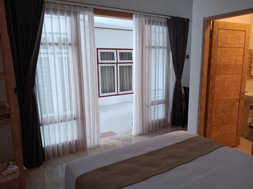 sypialnia z łóżkiem i dużym oknem w obiekcie Manuh Guest House w mieście Nusa Dua