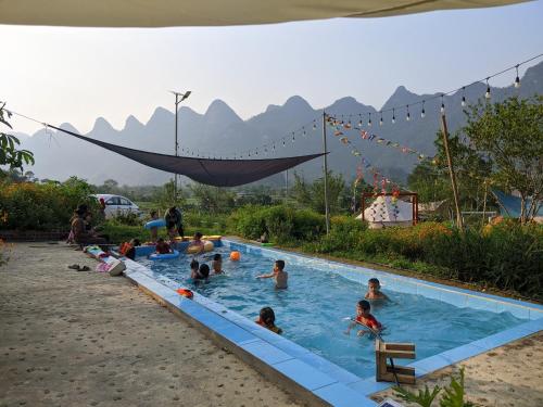 een groep mensen in een zwembad met bergen op de achtergrond bij Wind Hill Campsite in Ha Giang