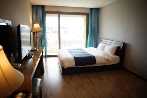 a bedroom with a bed and a television and a window at Hotel Master Daecheon in Boryeong