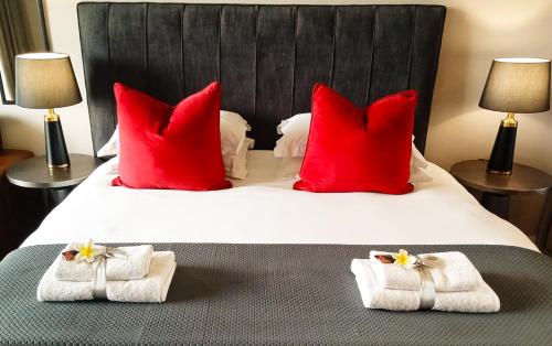 a bedroom with a large bed with red pillows and towels at Menlyn Maine Residences - Paris king sized bed in Pretoria