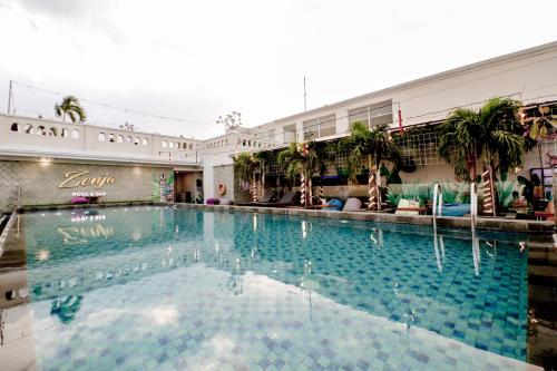 a large swimming pool in a building with palm trees at Zigna Kampung Batik in Solo