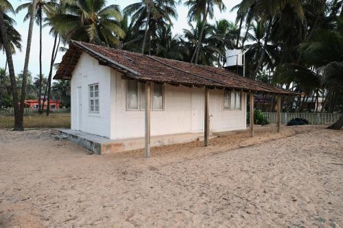 a small white house on the beach with palm trees at GB Beach house in Udupi
