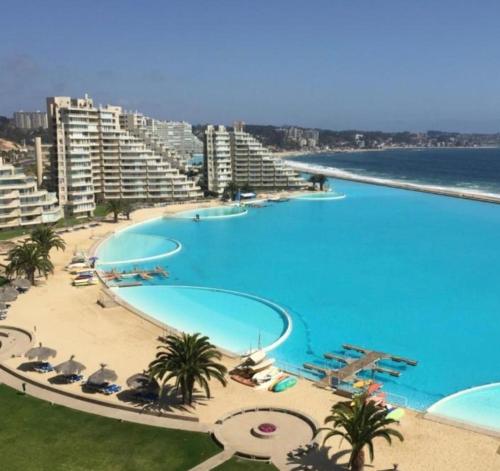 a large swimming pool next to a beach with buildings at Departamento San Alfonso del Mar, primer piso in Algarrobo