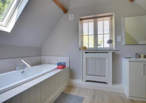 a bathroom with a bath tub and a window at Middle Barn in Leigh