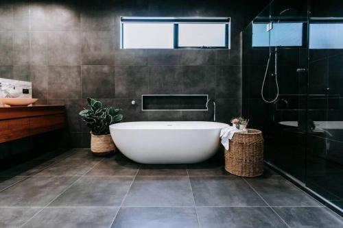 a bathroom with a white tub and a shower at The Moonah Residence in Fingal