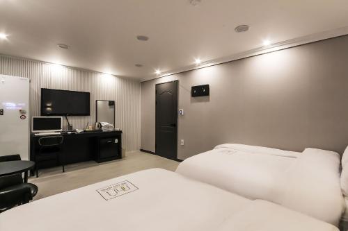 a hotel room with two beds and a television at Hotel The City in Gwangju