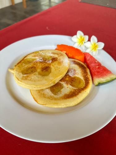 a plate with two pancakes and fruit on a table at Trawangan Oasis in Gili Trawangan