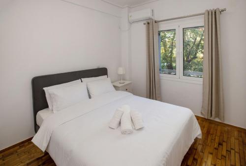a bedroom with a white bed with two towels on it at Newly Remodeled Dream Condominiun in Kifisia with Garden & Grass Lawn in Athens