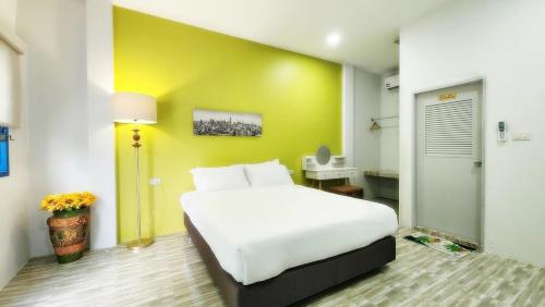 ein Schlafzimmer mit einem weißen Bett und einer gelben Wand in der Unterkunft บ้านเพิงโฮมสเตย์ in Ban Khuan Rai