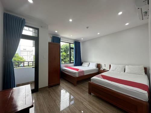 a bedroom with two beds and a desk and a window at OYO 1224 Motel Phuong Linh in Danang