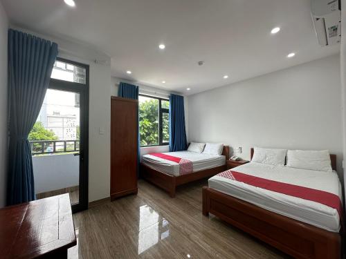 a bedroom with two beds and a desk and a window at OYO 1224 Motel Phuong Linh in Da Nang