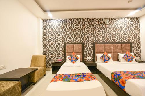 a hotel room with two beds and a couch at FabHotel Belwood in New Delhi