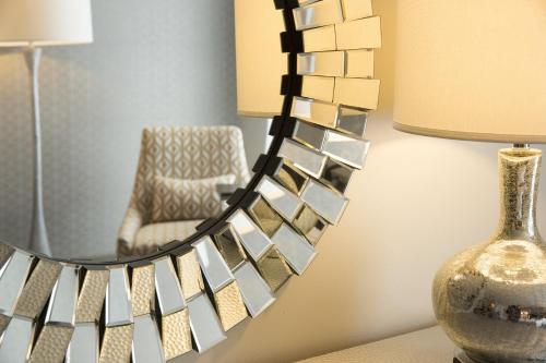 a mirror on a wall with a chair and a lamp at Crowne Plaza Chicago SW - Burr Ridge by IHG in Burr Ridge