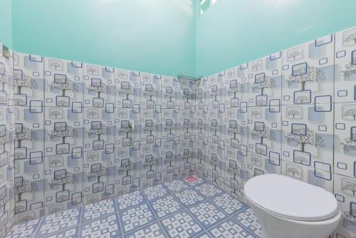 a bathroom with a toilet and a tiled wall at RedDoorz near Pantai Ujung Genteng in Cijaringao