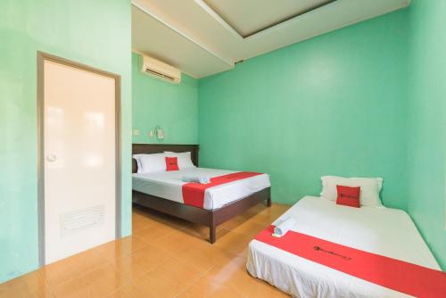 - 2 lits dans une chambre aux murs verts dans l'établissement RedDoorz near Pantai Ujung Genteng, à Cijaringao