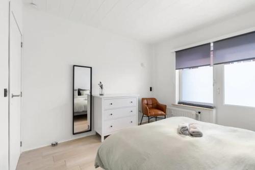 una camera con letto, specchio e sedia di Sunny Apartment 500m from the beach Oostend a Ostenda