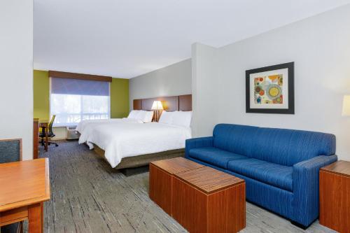 a hotel room with a bed and a blue couch at Holiday Inn Express & Suites Jacksonville South - I-295 by IHG in Jacksonville