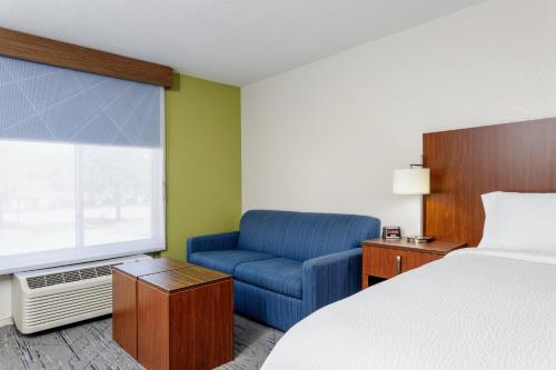 a hotel room with a bed and a blue chair at Holiday Inn Express & Suites Jacksonville South - I-295 by IHG in Jacksonville