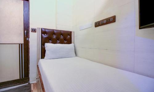 a small bedroom with a white bed with a wooden headboard at ZEST STAYS - MEADOW INN 1058 in Mumbai
