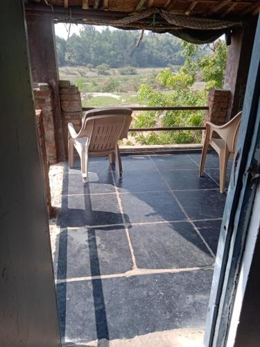 two chairs sitting on a porch with a view at River view home Hampi in Hampi