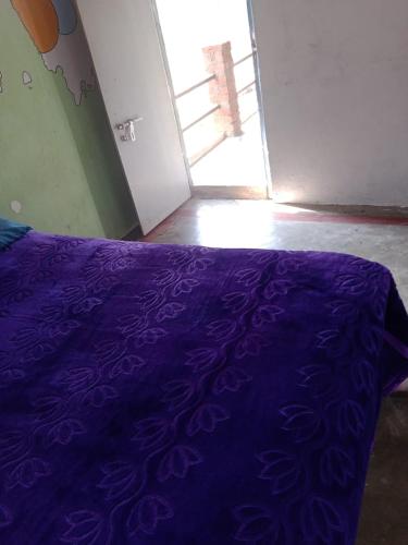 a bed with a purple comforter in a room at River view home Hampi in Hampi