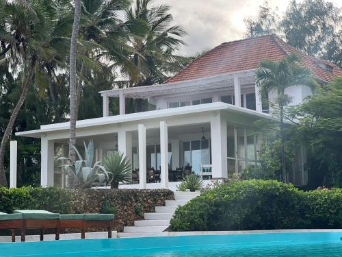 a white house with a swimming pool in front of it at BEACH FRONT VILLA in Malindi