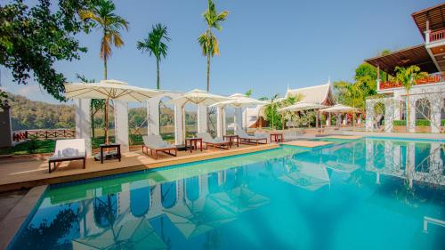 a pool at a resort with chairs and umbrellas at Relaxful Hotel泊岸酒店 in Luang Prabang