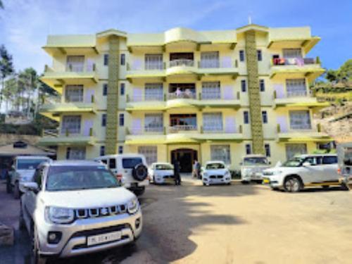 a large yellow building with cars parked in front of it at DAMEKI GUEST HOUSE , Shillong in Shillong