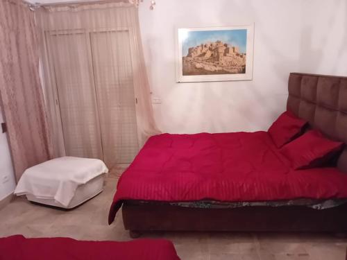 Douar GabrejelliにあるVilla il Cavaliereのベッドルーム(赤いベッド1台、椅子付)