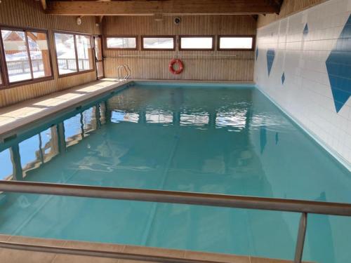a large indoor swimming pool with blue water at Appartement dans un chalet, résidence avec piscine in La Toussuire
